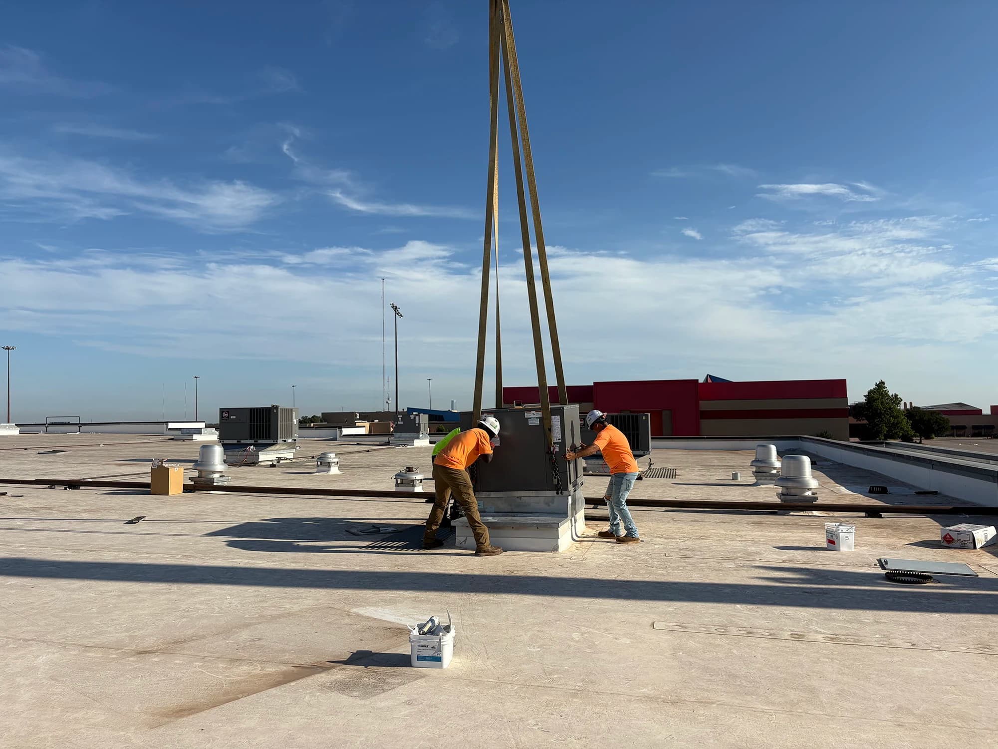 RCI technicians guiding a rooftop unit into place