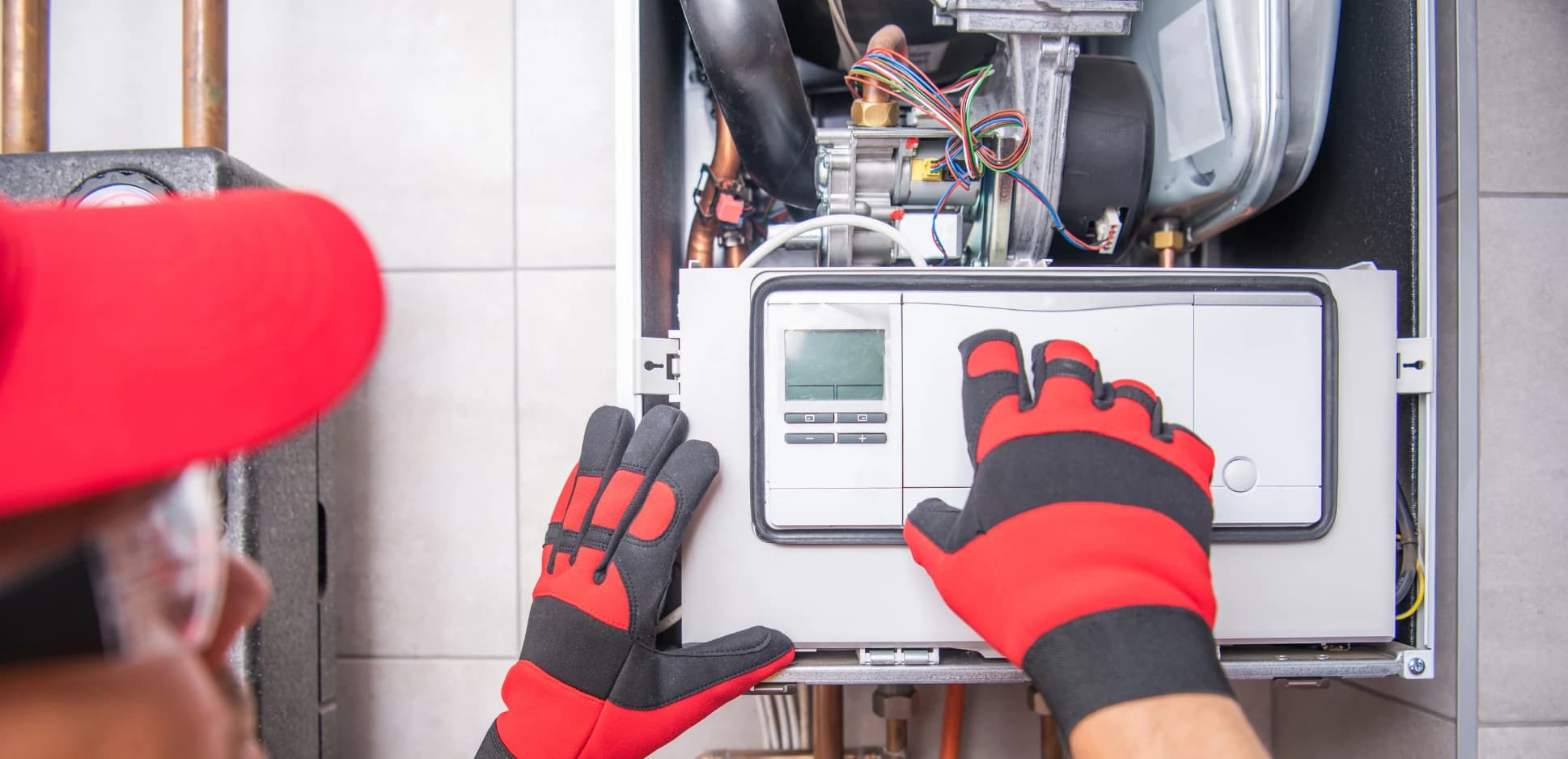 Technician in work gloves adjusting a wall thermostat during a heating repair call