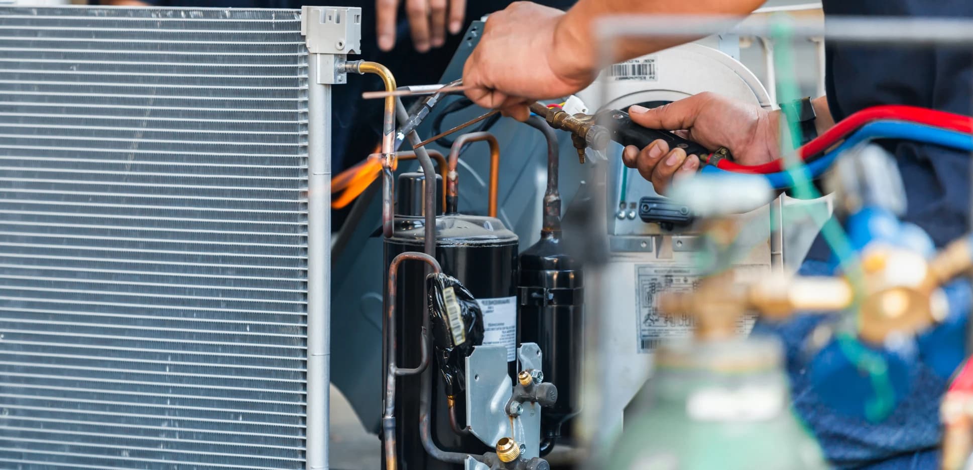 Technician checking refrigerant pressures on an air conditioner with gauges
