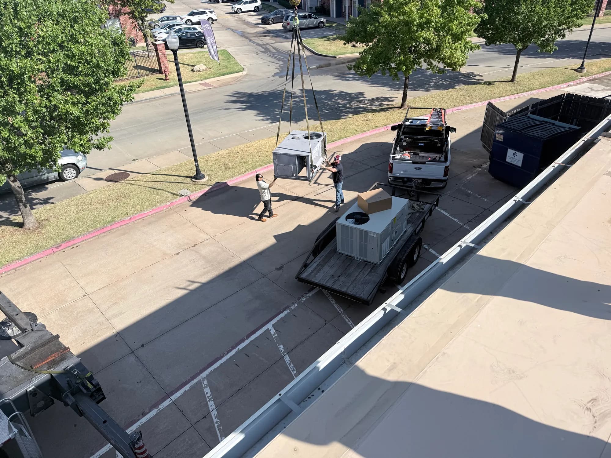 RCI crew guiding a crane-lifted rooftop HVAC unit down to a trailer at an Oklahoma commercial building